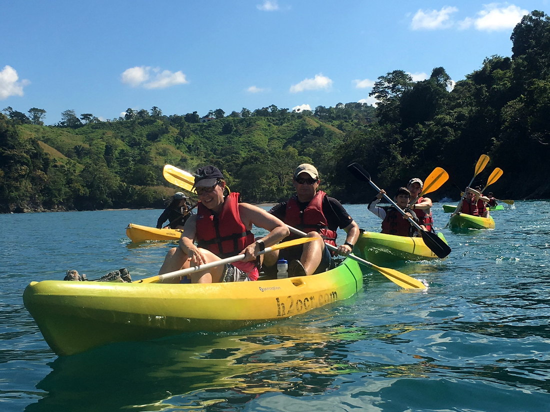 Guests paddling yellow H2O sea kayaks along the green coast of Manuel Antonio