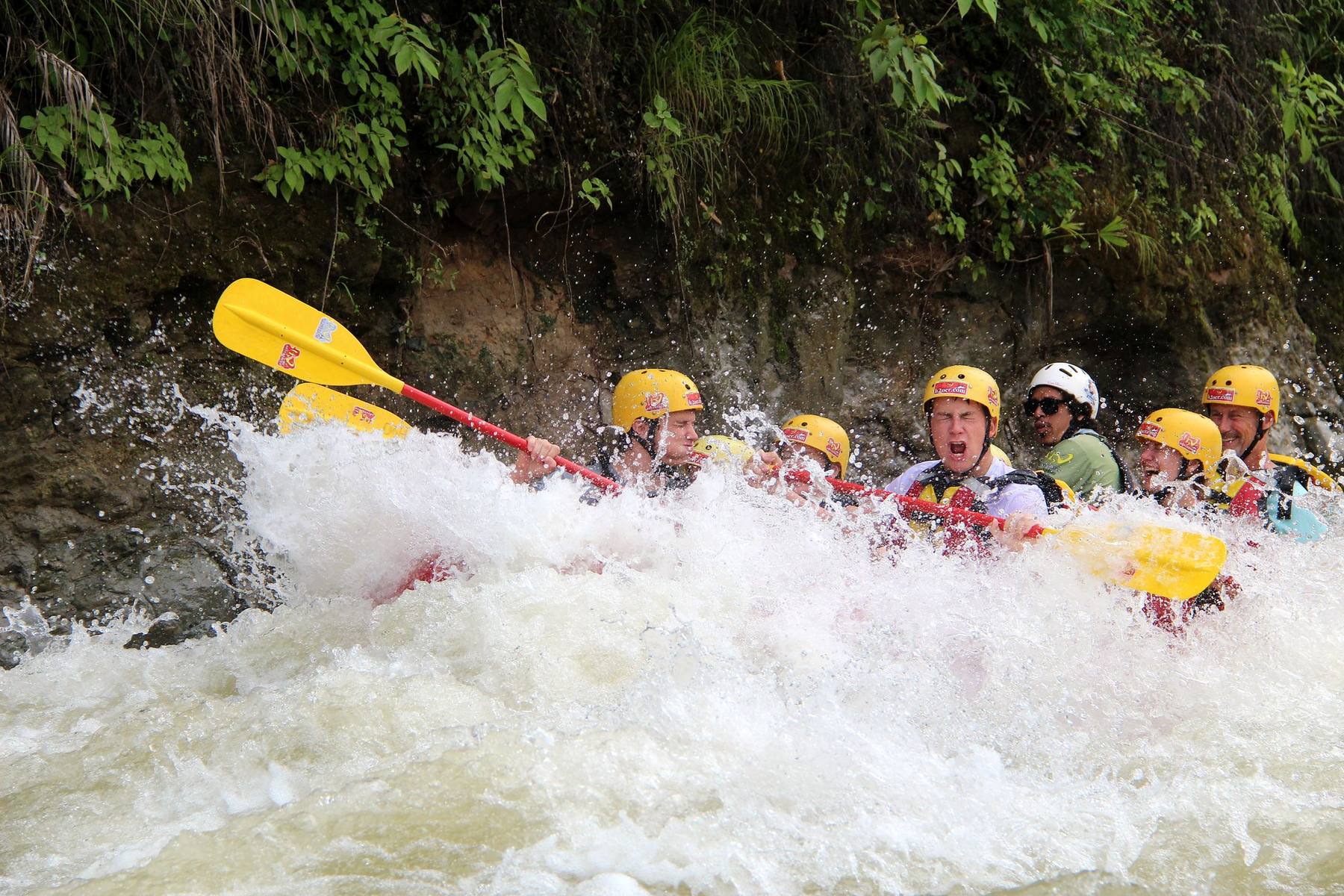 A wall of white water over a family raft on the Savegre