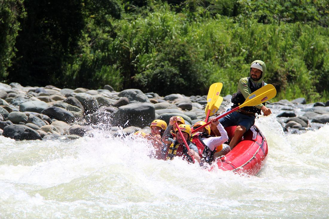 Raft running a wave on the Savegre with the guide at the back