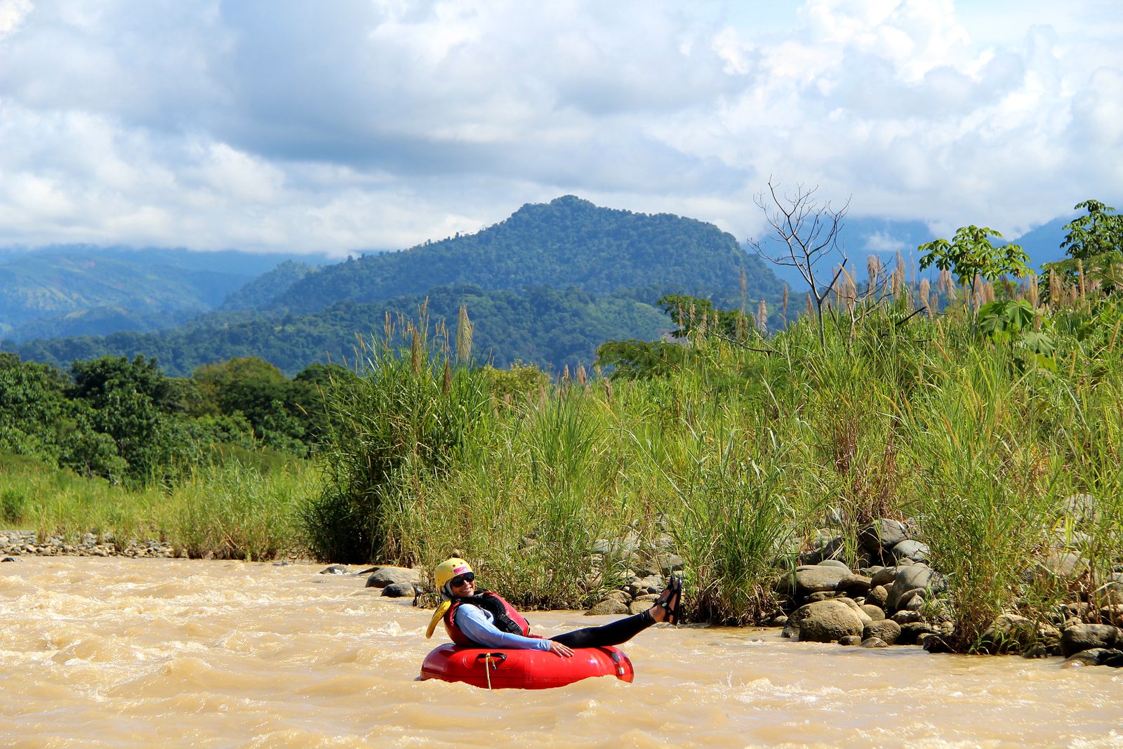 A guest floats below green hills and mountains on the lower Naranjo